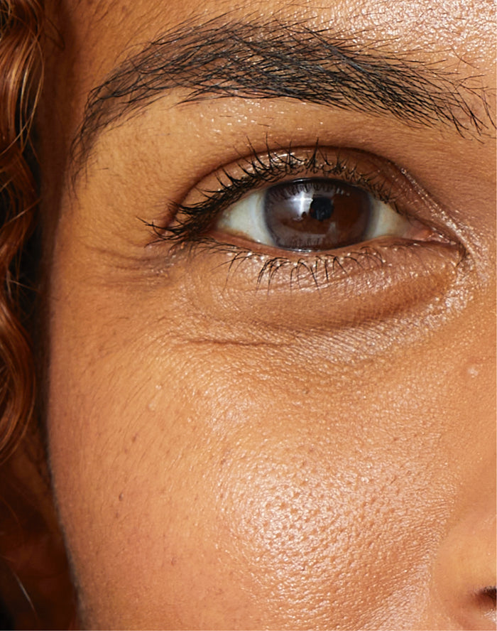 Primer plano de un ojo y una mejilla, resaltando la textura de la piel y las pestañas naturales-perfecto para rutina facial o cuidado facial líneas.